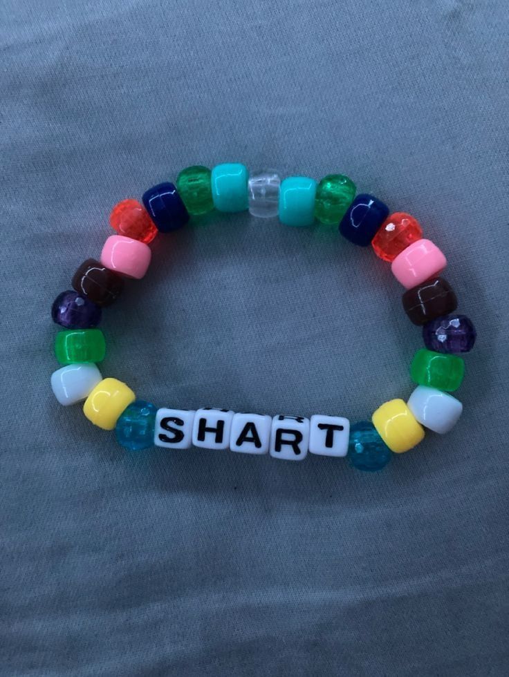 a colorful bracelet with the word smart written in white letters on it, sitting on top of a bed