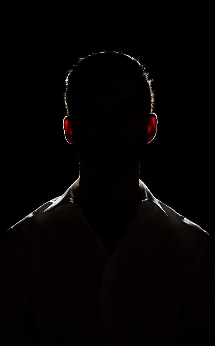 the silhouette of a man with red eyes is shown in the dark, while his head is turned to the side