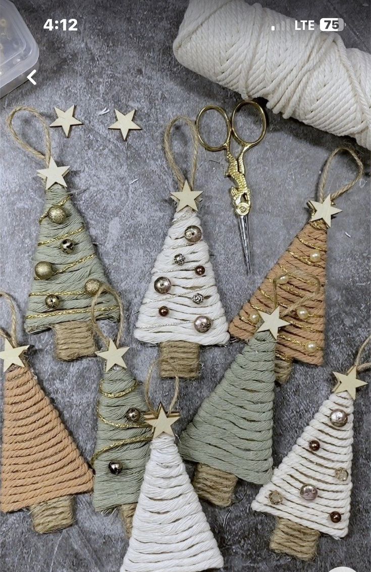 christmas tree ornaments made out of yarn and twine are displayed on a table with scissors