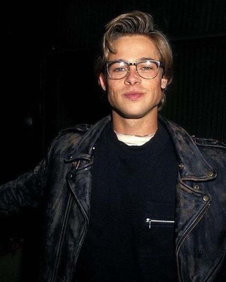 a young man wearing glasses and a leather jacket