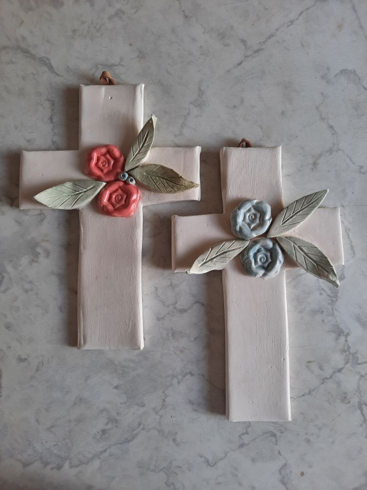 three wooden crosses decorated with flowers on top of a marble countertop, one painted pink and the other blue