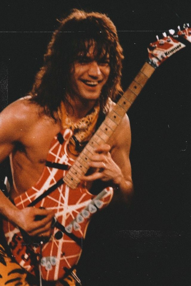 a man with long hair playing an electric guitar