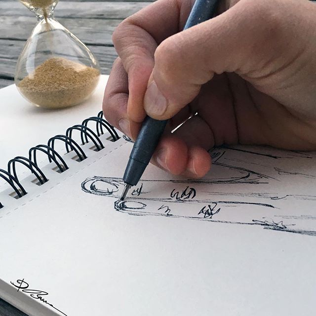 a hand holding a pen writing on top of a notebook next to an hourglass