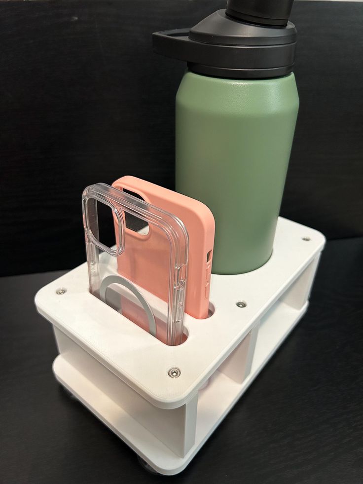 two cell phones and a water bottle are sitting on the holder for each other's phone