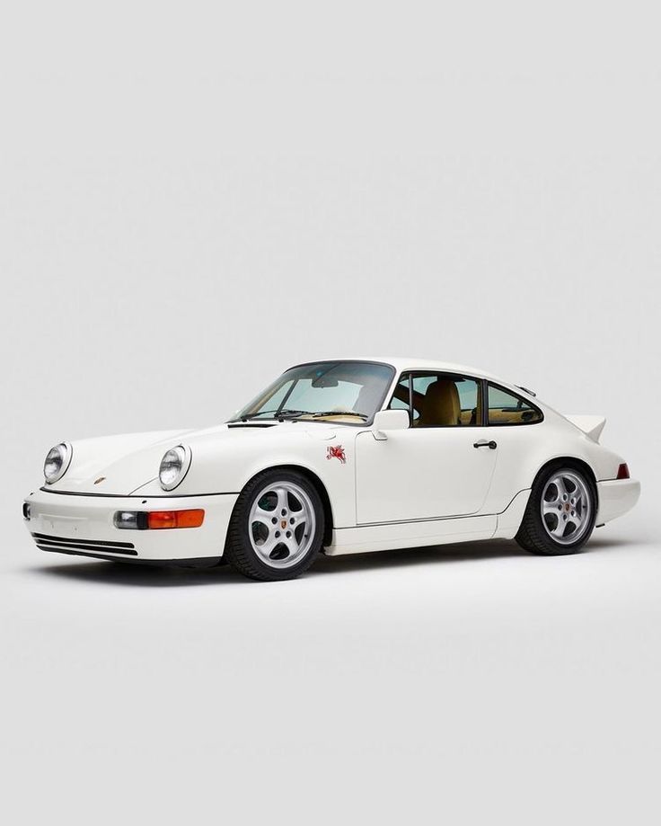 a white porsche parked in front of a gray background