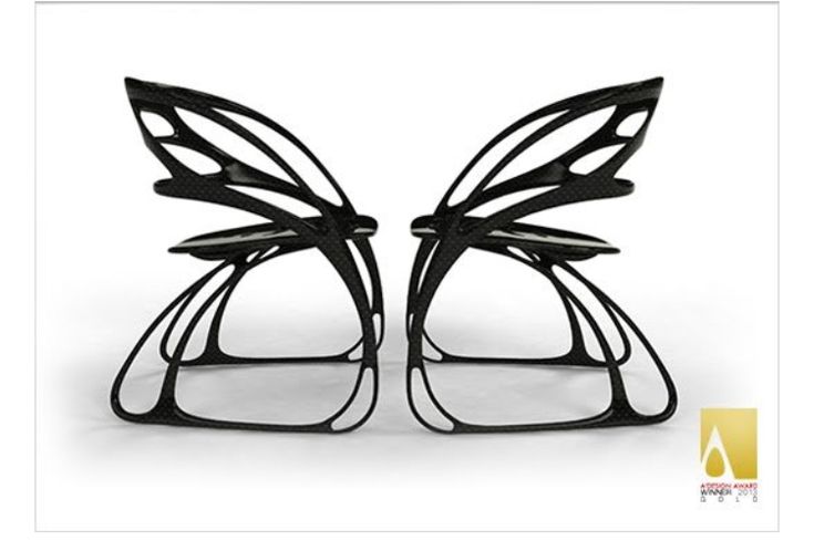 two black metal sculptures sitting next to each other on a white surface and one is shaped like a butterfly