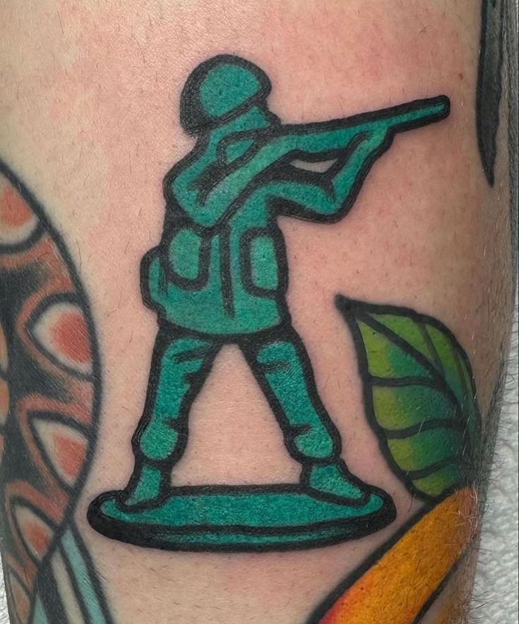 a man with a green army tattoo on his leg holding a baseball bat and ball