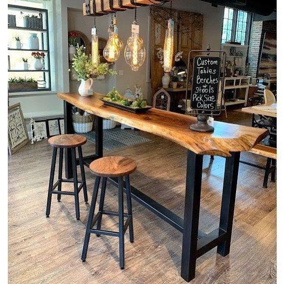 a wooden table sitting inside of a store next to two stools and a chalkboard sign