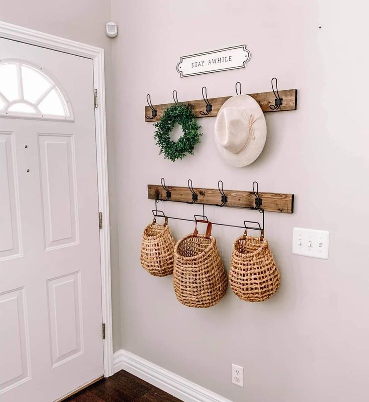 the entryway is clean and organized with baskets, hats, and wreaths on hooks