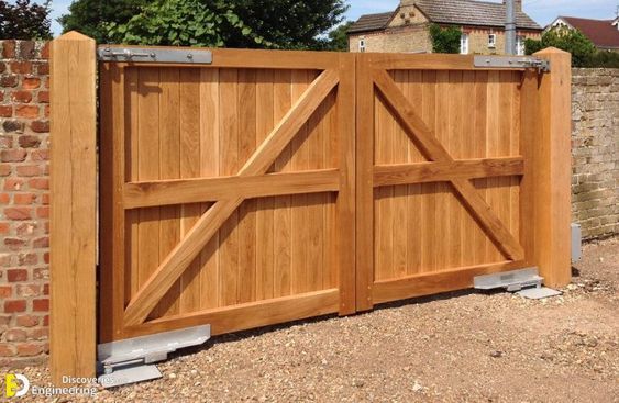 a large wooden gate with two sliding doors on each side and brick wall in the background