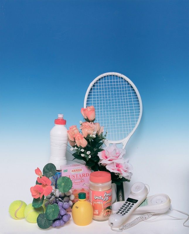 a tennis racket, flowers and other items on a white table with blue background