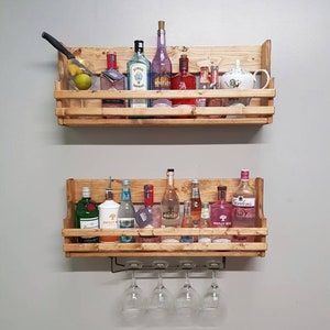 two wooden shelves with wine glasses and liquor bottles on them, hanging from the wall