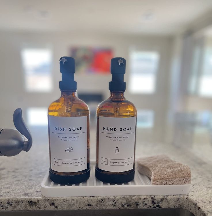 two bottles of soap sitting on top of a counter