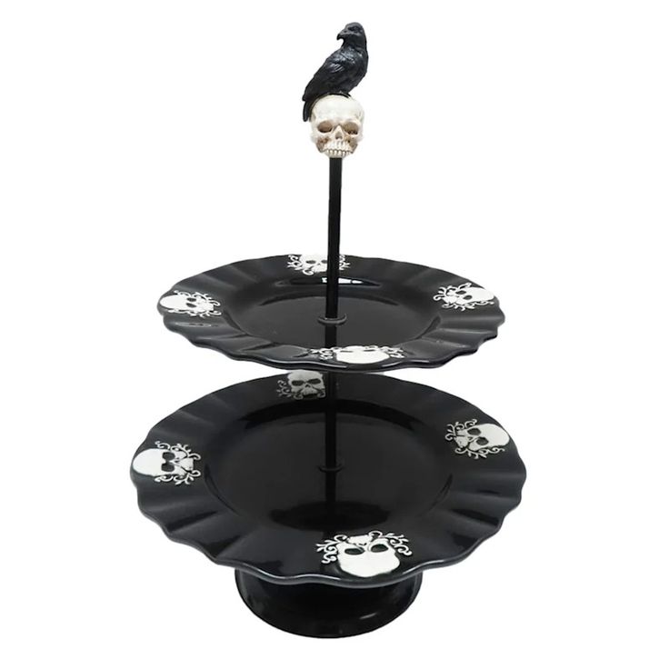 two tiered plates with skulls on them and a black bird perched on the top