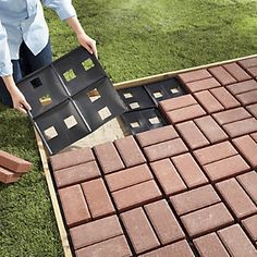 a woman is placing bricks into the ground