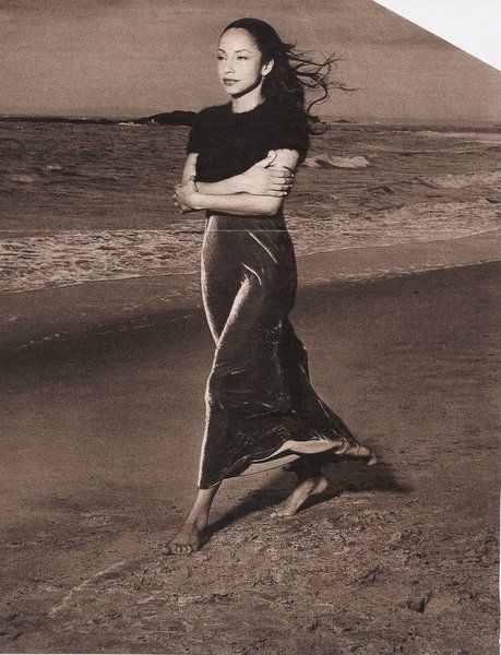 a black and white photo of a woman on the beach with her hair blowing in the wind