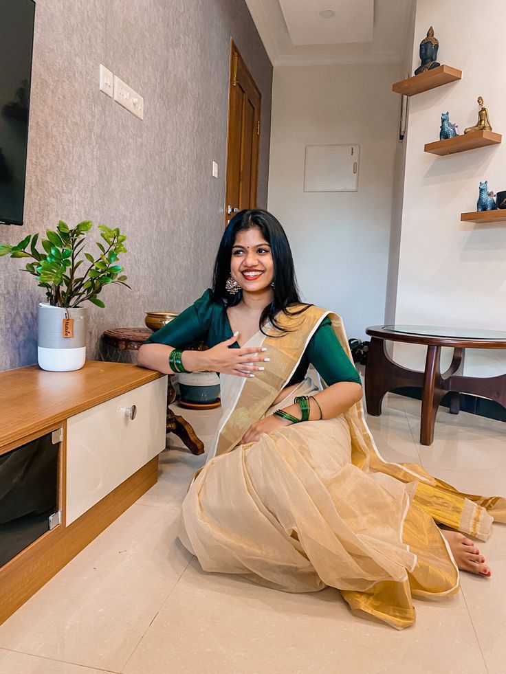 a woman sitting on the floor in a living room holding a piece of paper and smiling