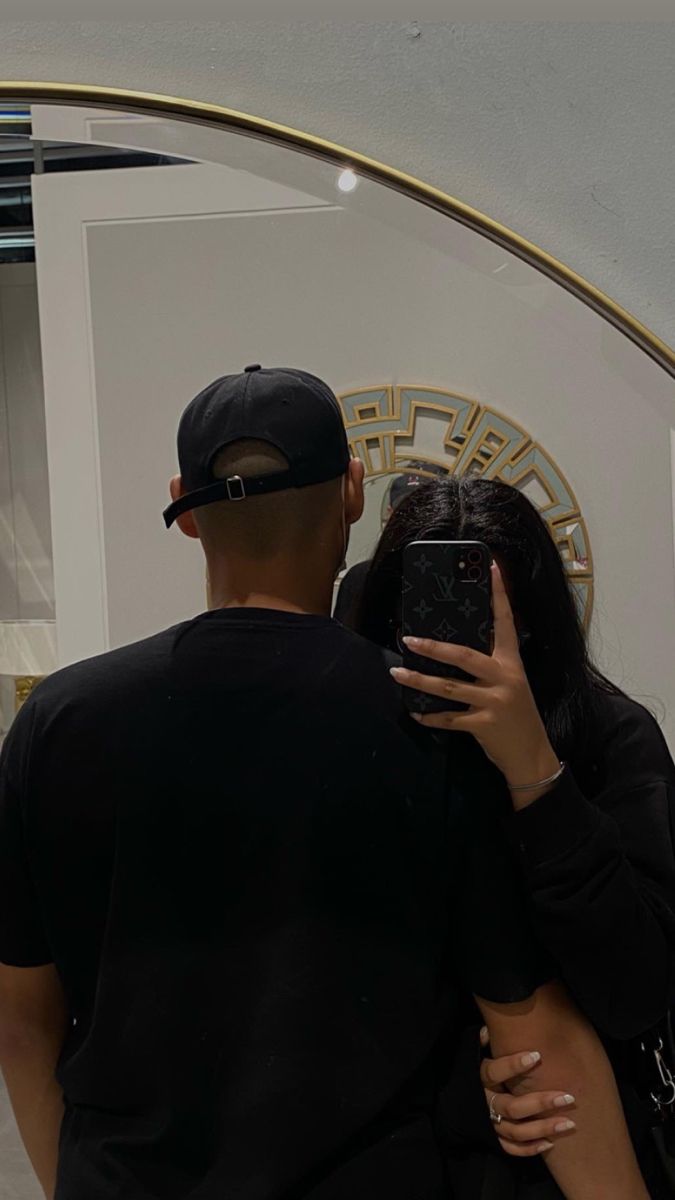 a man and woman standing in front of a mirror taking a selfie with their cell phone