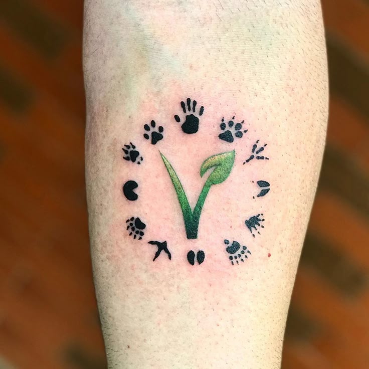 a person with a tattoo on their leg that has paw prints and leaves around it