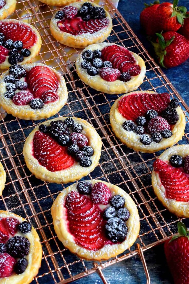 fresh fruit tarts on cooling racks with strawberries and blueberries in the background