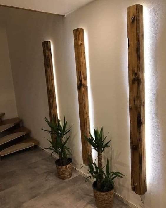 three potted plants sitting on the floor in front of two wooden pillars with light coming through them