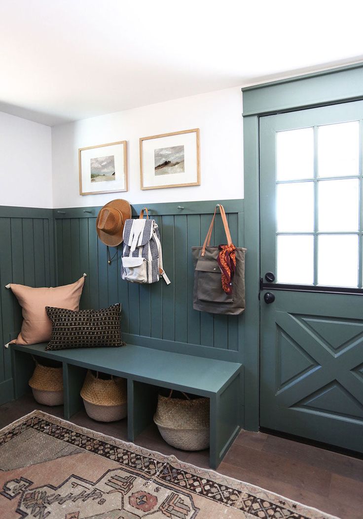 a green bench sitting in front of a door with two hats hanging on it's hooks