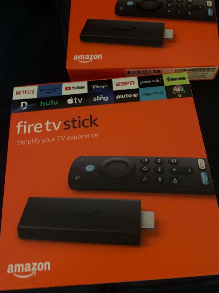 two black remote controls sitting on top of an orange box with the amazon fire tv stick in it