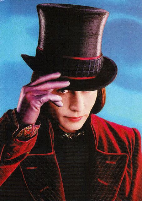 a man in a top hat and red jacket holding his hand to his face while looking at the camera