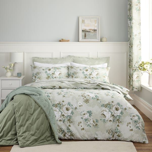 a bed with white and green comforters in a bedroom next to a window,