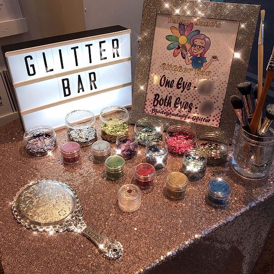 there are many different types of glitters on the table with a lighted sign behind them