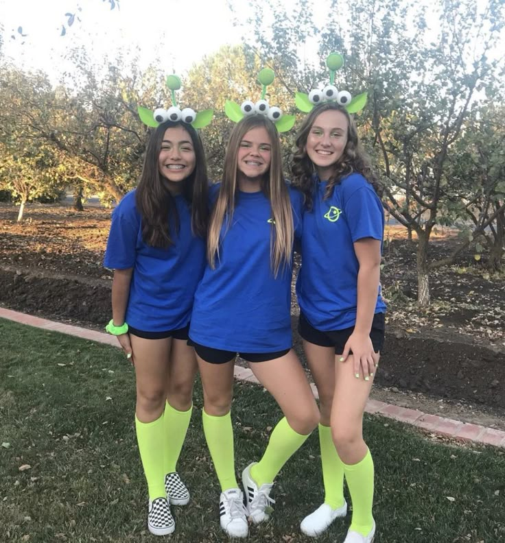 three girls in blue shirts and green socks posing for the camera