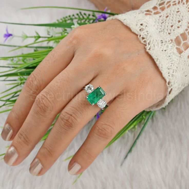 a woman's hand with an emerald and diamond ring