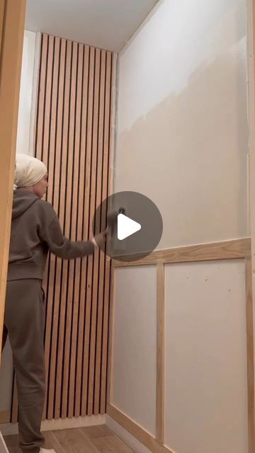 a woman is painting the walls in her house with white paint and wood slats