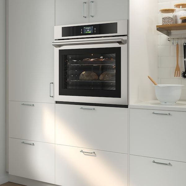 a white kitchen with an oven built into the wall