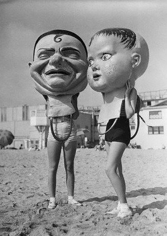 two children standing in the sand with masks on their heads and one is wearing a bathing suit