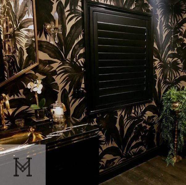 the bathroom is decorated in black and white with palm leaves on the wall behind it