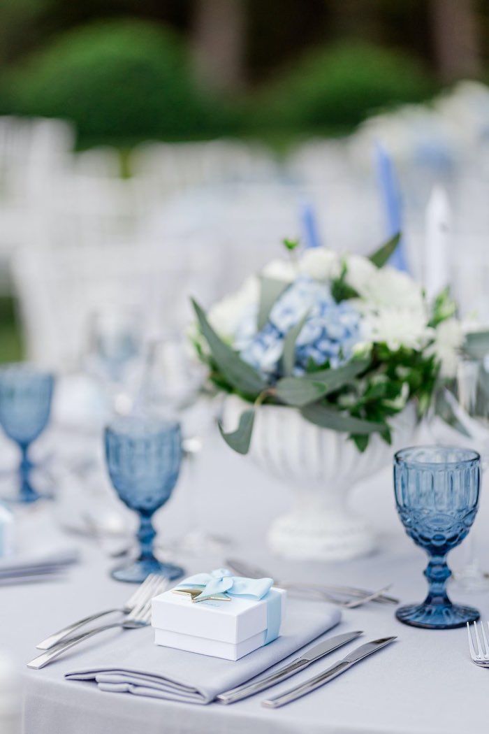 the table is set with blue and white dishes, silverware, and napkins