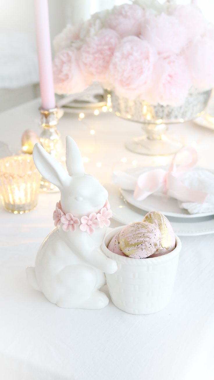 a white bunny figurine sitting next to a small cup filled with pink candy