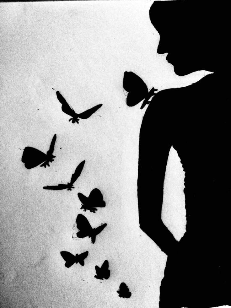 a woman standing in front of a flock of butterflies