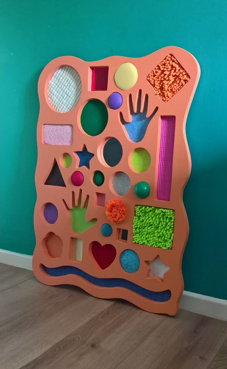 an orange play mat with different shapes and sizes on it in front of a blue wall