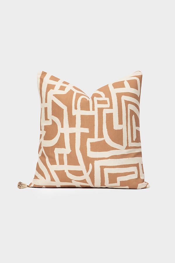 a brown and white pillow with an abstract design on the front, sitting against a white background