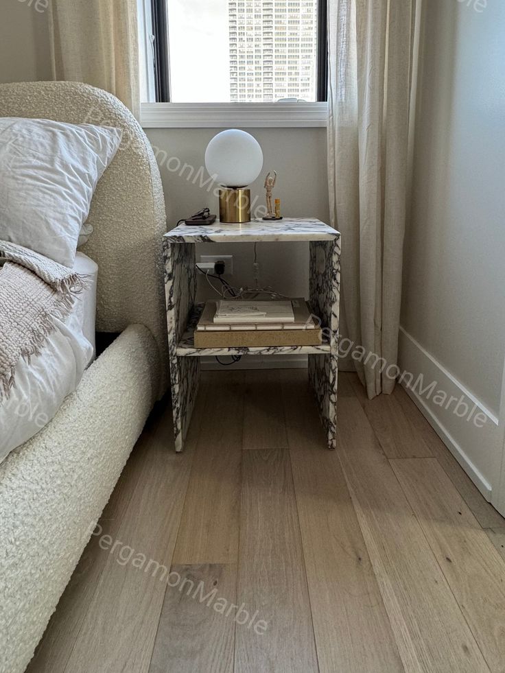 a white bed sitting next to a window in a bedroom on top of a hard wood floor