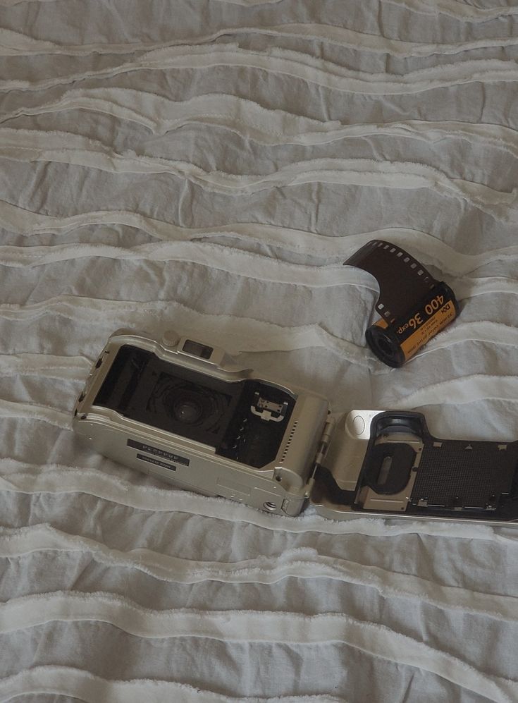 two cameras laying on top of a white bed