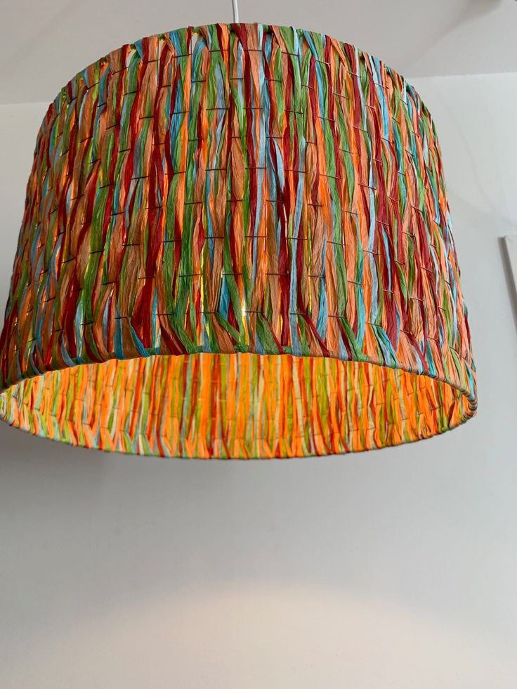 a multicolored lamp shade hanging from a ceiling in a room with white walls