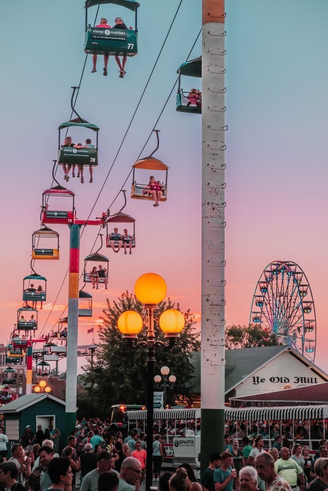 a crowd of people sitting on top of a ferris wheel at dusk in an amusement park