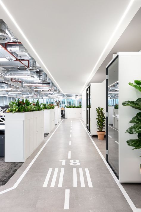 an office building with plants and planters on the floor, along with white walls