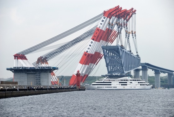 a large white boat in the water next to a bridge with red and white stripes on it