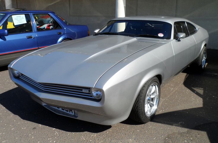 a silver muscle car parked next to other cars