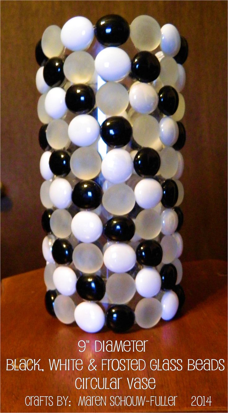 a black and white glass bead vase sitting on top of a wooden table