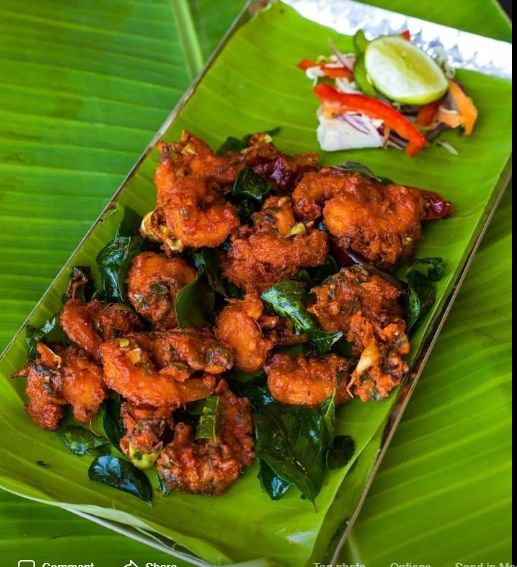 some food is sitting on a leafy green plate and next to a side dish